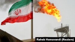 FILE PHOTO: A gas flare on an oil production platform in the Soroush oil fields is seen alongside an Iranian flag in the Persian Gulf.