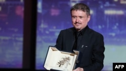 რუმინელი კინორეჟისორი კრისტიან მუნჯიუ კანის კინოფესტივალის მთავარი პრიზით ხელში.  23 მაისი, 2026 წელი