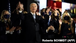 U.S. President-elect Joe Biden with his wife, Jill Biden (right), and family members salute the crowd on stage after delivering remarks in Wilmington, Delaware, on November 7 and being declared the winner of the presidential election. 