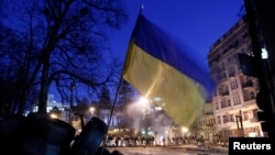 The Ukrainian national flag flies above an antigovernment barricade that faces a cordon of riot police in Kyiv on February 3.