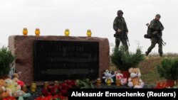 Russia-backed separatist fighters walk past a memorial to victims of the Malaysia Airlines Flight 17 plane crash outside the village of Hrabove in eastern Ukraine.