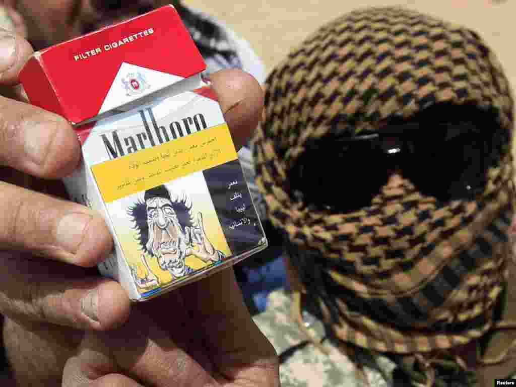 A rebel fighter holds up a packet of cigarettes with a "health warning" sticker that features a caricature of Libyan leader Muammar Qaddafi near the front line along the western entrance of Ajdabiya on April 18. Photo by Amr Abdallah Dalsh for Reuters