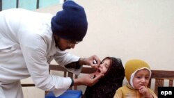 A Pakistani health worker administers a polio vaccine to a child.