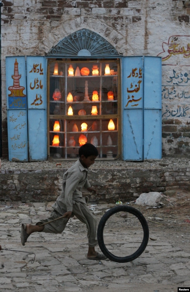 Một cậu bé người Pakistan chạy qua một cửa hàng bán đèn và đồ trang trí. & Nbsp;