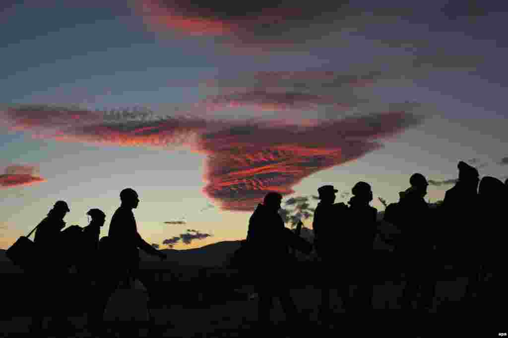 Migrants are silhouetted while waiting for permission to board a train heading to the Serbian border, near the city of Gevgelija, Macedonia. (epa/Valdrin Xhemaj)