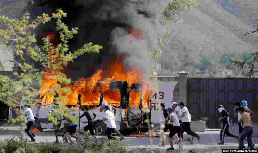 Atambaev supporters run past a flaming vehicle in Koi-Tash village. 