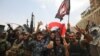 Members of the Iraqi federal police dance and wave their country's national flag in celebration in the Old City of Mosul on July 8.