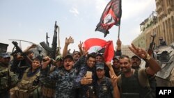 Members of the Iraqi federal police dance and wave their country's national flag in celebration in the Old City of Mosul on July 8.