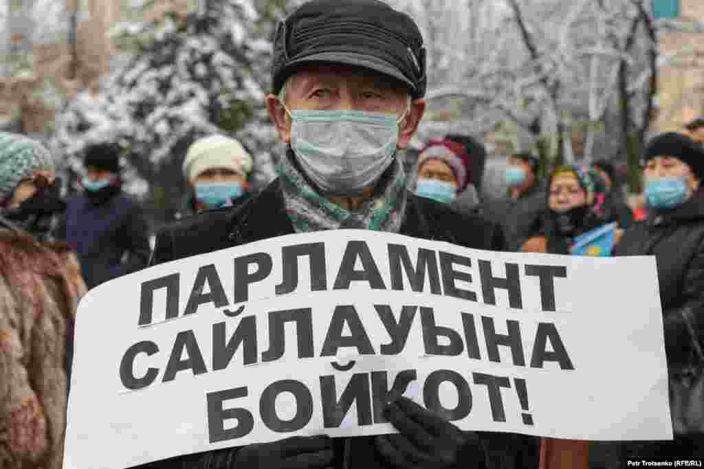 Мужчина с плакатом, призывающим бойкотировать предстоящие парламентские выборы в Казахстане.