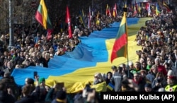 Люди несуть гігантський український прапор на знак протесту проти російського вторгнення в Україну під час святкування незалежності Литви. Вільнюс, 11 березня 2022 року