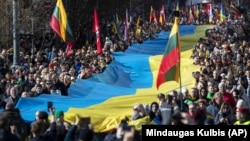  Люди несуть гігантський український прапор на знак протесту проти російського вторгнення в Україну під час святкування незалежності Литви. Вільнюс, 11 березня 2022 року