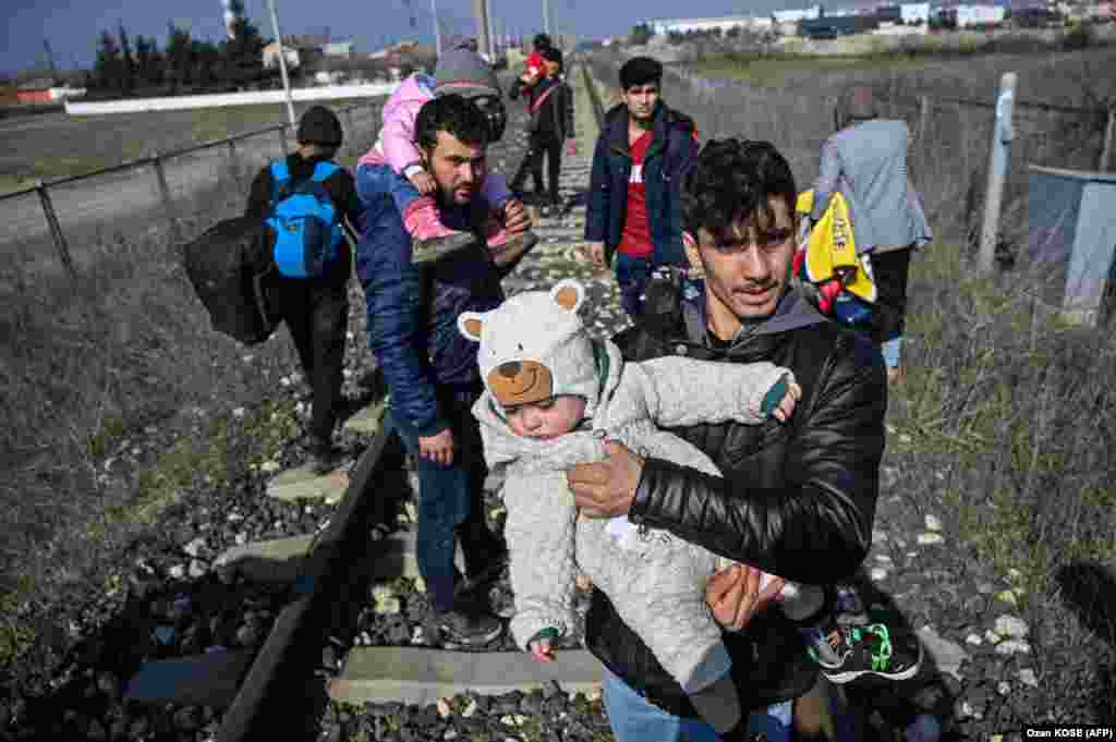 A migrant carries his baby as they walk on a railway toward the Meric river, near Edirne, to take a boat to attempt to enter Greece by crossing the river on March 1.