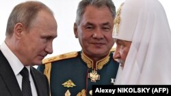 Russian President Vladimir Putin (left), Russian Patriarch Kirill of Moscow (right), and Russian Defense Minister Sergei Shoigu talk while visiting a marine church in St. Petersburg. (file photo)