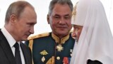 RUSSIA – Russian President Vladimir Putin (L), Russian Patriarch Kirill of Moscow (R) and Defence Minister Sergei Shoigu talk while visiting a marine church during Navy Day in Saint Petersburg on July 30, 2017