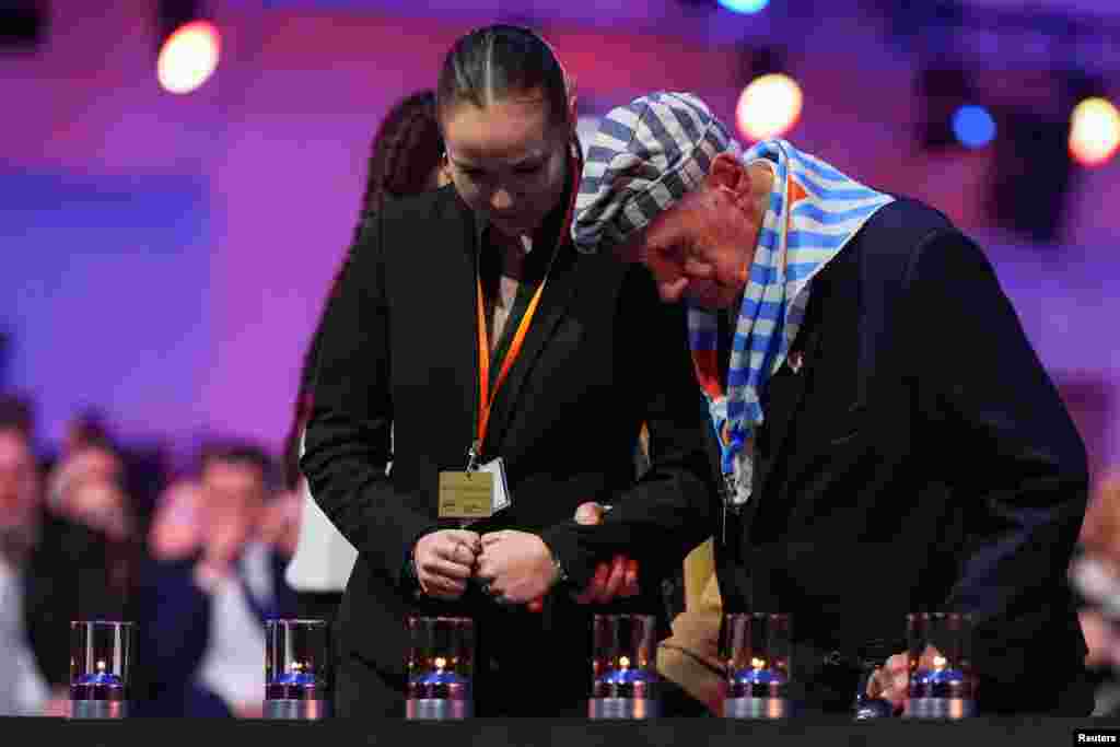 Un supraviețuitor al Holocaustului se uită la lumânări în timp ce este asistat în timpul unui eveniment de comemorare care marchează 80 de ani de la eliberarea lagărului de concentrare și exterminare nazist Auschwitz-Birkenau - 27&nbsp; ianuarie 2025.&nbsp;&nbsp;