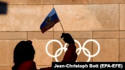 A supporter waves a Russian flag in front of the logo of the International Olympic Committee at its headquarters in Pully, near Lausanne, Switzerland.