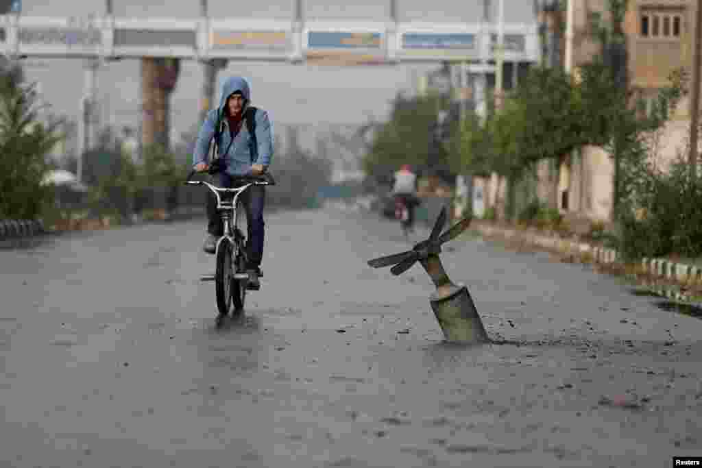 A Syrian man rides his bicycle near what activists said was an exploded cluster bombshell in Damascus on November 5. (Reuters/​Bassam Khabieh)