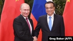 Russian President Vladimir Putin (L) and Chinese Premier Li Keqiang shake hands during a meeting in the Great Hall of the People in Beijing on June 8.