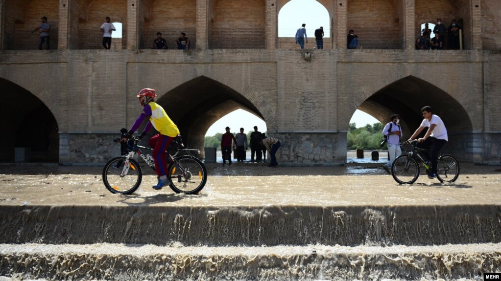 دو دوچرخه‌سوار روز ۲۰ تیرماه پس از جاری شدن آب در زاینده‌رود در آن رکاب می‌زنند.