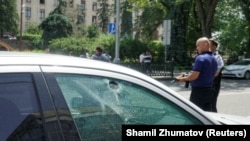 Вооруженные сотрудники полиции рядом с автомобилем, в окне которого видно отверстие от пули. Алматы, 18 июля 2016 года.