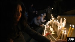 Женщина зажигает свечу в центре Еревана в память шести членов семьи, убитых солдатом Валерием Пермяковым в Гюмри, 13 января 2015