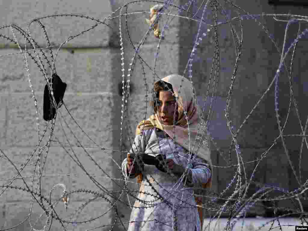 An Afghan girl looks on from behind barbed wire as Afghan forces investigate the site of a suicide attack in Kabul on November 12. A suicide car bomber attacked a NATO convoy near the new parliament building in the Afghan capital, police and the coalition said, the first attack in Kabul in three months after security was increased. Photo by Omar Sobhani for Reuters