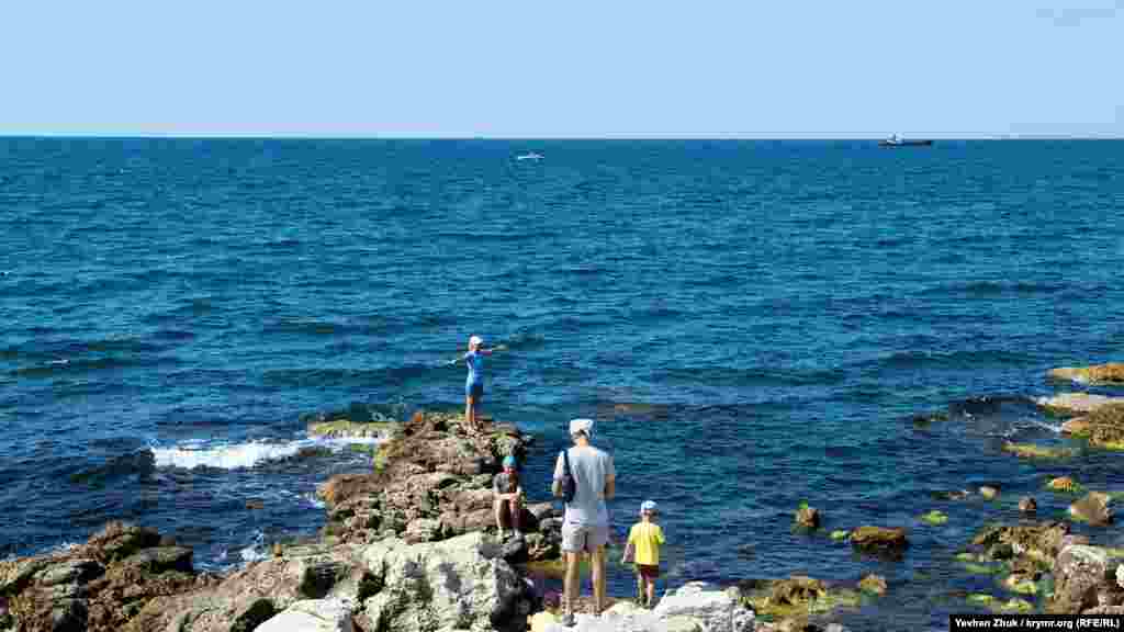 Туристы фотографируются на камнях у моря