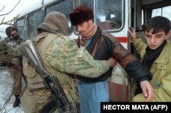 Российский солдат проверяет пассажиров выезжающего из Чечни автобуса в поисках оружия на границе с Дагестаном. 24 декабря 1994 года