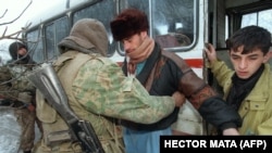 Российский солдат проверяет пассажиров автобуса, выезжающего из Чечни, пытаясь найти оружие на границе с Дагестаном 24 декабря 1994 года