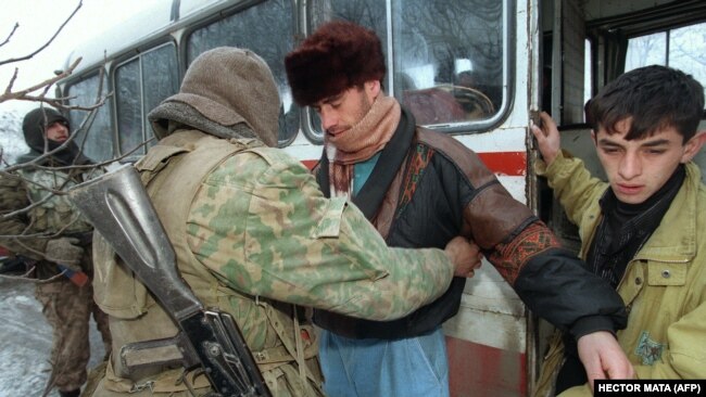Российский солдат проверяет пассажиров автобуса, выезжающего из Чечни, пытаясь найти оружие на границе с Дагестаном 24 декабря 1994 года.