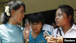 Pro-democracy leader Aung San Suu Kyi (left) talks to reporters in front of the National League for Democracy Party head office in Yangon on April 22.
