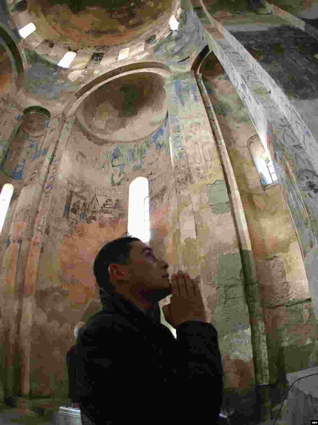 An Armenian man prays after the 2007 opening ceremony.