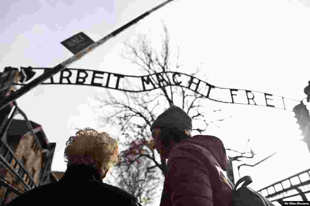 Jona Laks, survivor of Auschwitz concentration camp, and her granddaughter, Lee Aldar stand next to the gate with the slogan &quot;Arbeit macht frei&quot; (&quot;Work sets you free&quot;) as they start their visit at the Auschwitz death camp in Oswiecim, Poland January 26, 2020.