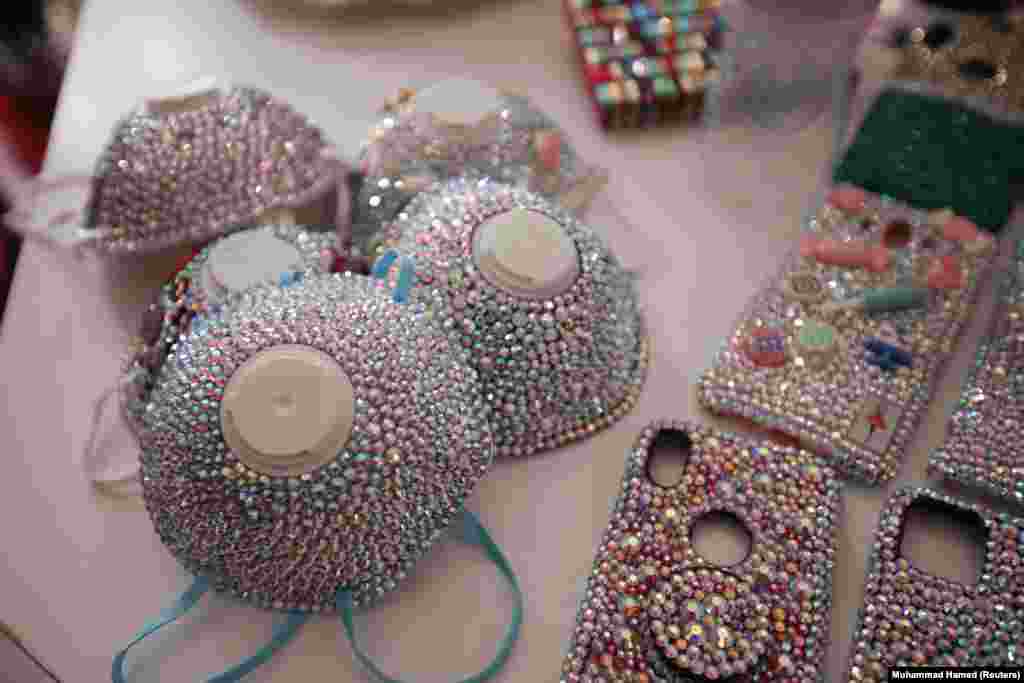 Crystal-covered face masks by designer Samia al-Zakleh are displayed along with smartphone cases at her shop in Amman, Jordan.