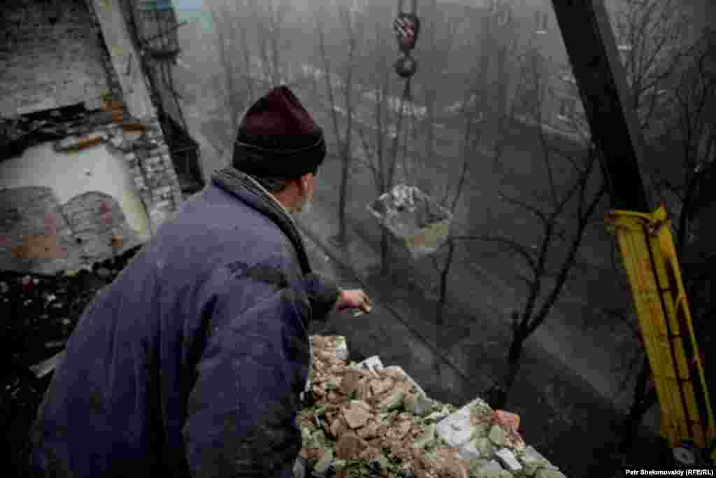 Workers clear rubble from a rooftop.