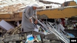 رجل يتفحص أنقاض مدرسة مدمرة في قرية قرب تكريت