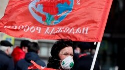 Pristalica Komunističke partije Rusije sa zaštitnom maskom za lice drži zastavu tokom ceremonije polaganja cvijeća na mauzolej osnivača sovjetske države Vladimira Lenjina, povodom 150. godišnjice njegovog rođenja, Moskva, 22. aprila 2020. godine