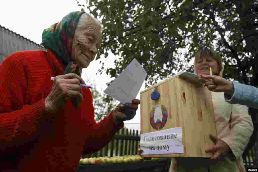 A woman reads a ballot before casting her vote into a portable ballot box in the village of Slobodschina.