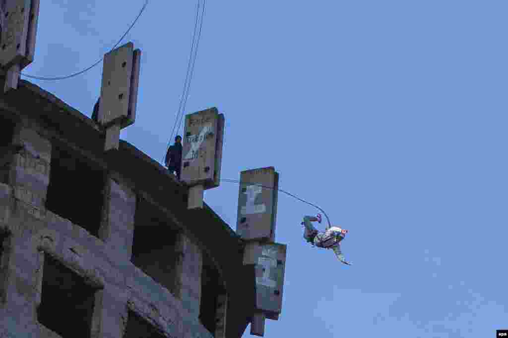 A man wearing a climbing harness and fixed to a rope, jumps from a 75-meter-high building near Chisinau. "Flying rope" jumping has become a popular unofficial sport among young Moldovans. (epa/Dumitru Doru)