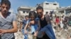 SYRIA -- A man carries a child rescued from rubble after Syrian regime and Russian air strikes in the rebel-held town of Nawa, about 30 kilometres north of Daraa in southern Syria on June 26, 2018.