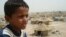 A displaced Iraqi child sits next to his tent at a refugee camp in Al-Najaf