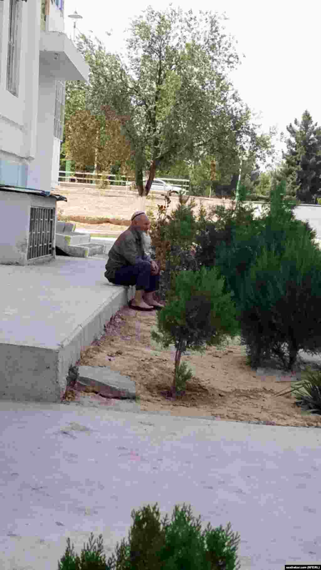 Jaýyň kölegesinde dynç alyp oturan ýaşuly bir adam. Aşgabat