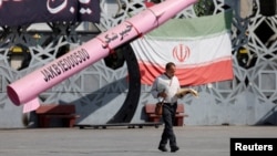FOTO DE ARHIVĂ: Un bărbat trece pe lângă o machetă simbolică a unei rachete iraniene, în Piața Imam Hussein din Teheran.