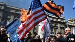 Vojisllav Shesheli duke e mbajtur flamurin amerikan që digjet në përvjetorin e 16-të në bombardimeve të NATO-s kundër caqeve serbe në Kosovë dhe Serbi