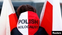 Žena drži poljsku zastavu dok dolazi u bivši njemački koncentracioni logor Aušvic (Auschwitz)