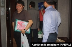 Сотрудники спецслужб уносят после обыска материалы из офиса оппозиционной организации «Балга» Алматы, 30 мая 2013 года.