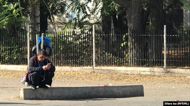 Мужчина, сидящий вдоль дороги в ожидании предложений о работе. Шымкент, 21 октября 2019 года.