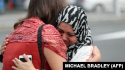 Residents hug after paying respects at a mosque in Auckland, New Zealand, following the attacks in Christchurch.