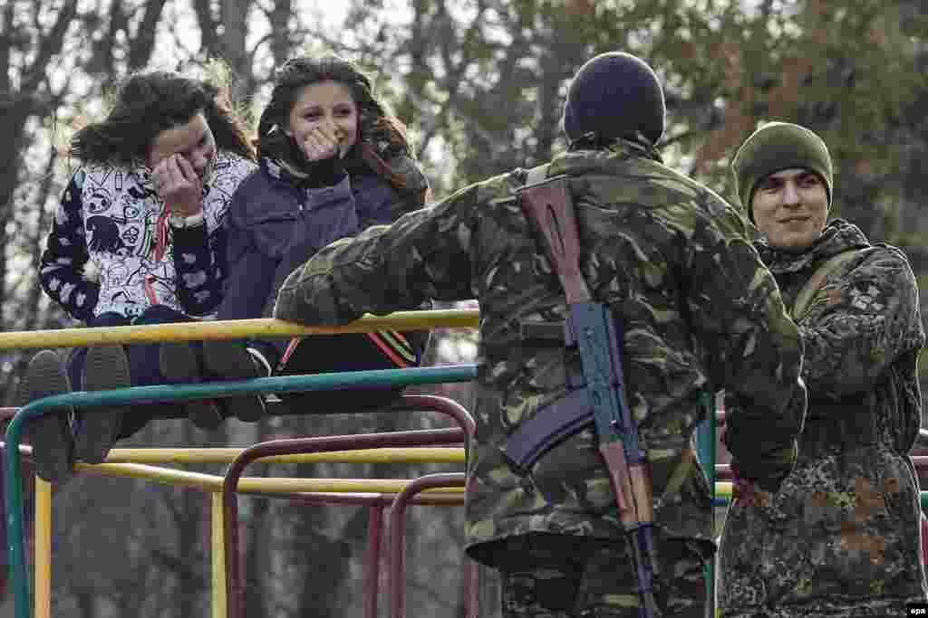 Молоді українські солдати жартують з дівчатами на спортмаданчику. Місто Ізюм, 16 березня 2015 року&nbsp;