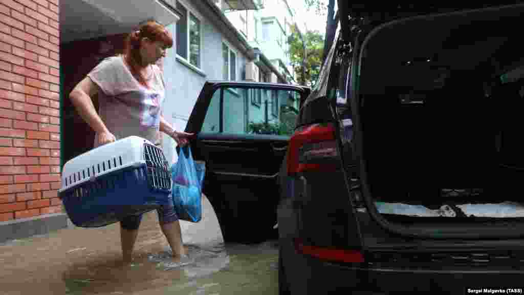 Женщина с переноской для домашних животных в руках готовится к отъезду из зоны затопления на одной из центральных улиц города